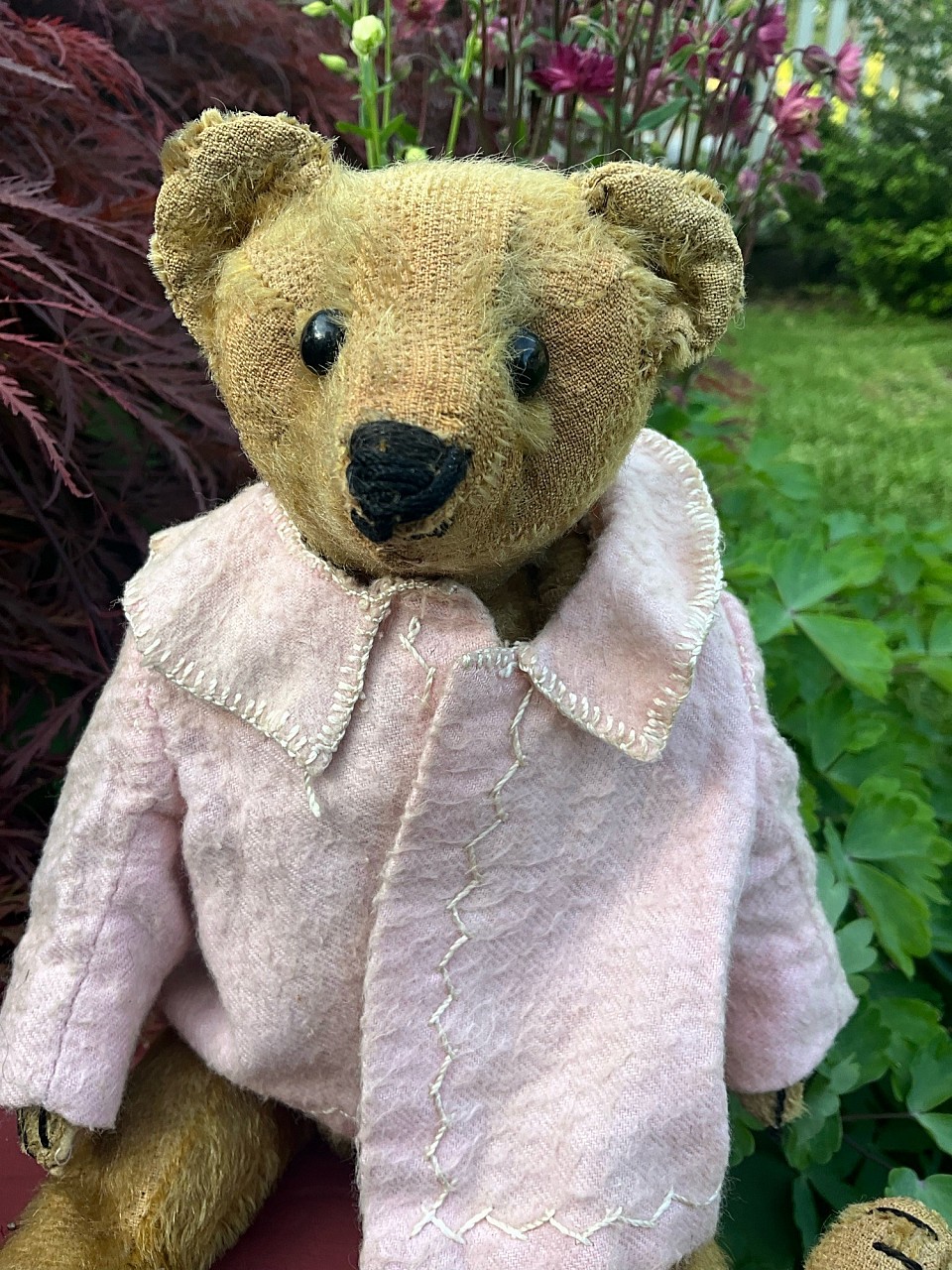 Early 11” bear with unique profile in antique pink jacket with sweet feather stitching. This pre 1910 bear looks to have originally been a mustard color. His tummy squeaker is now silent and he has some naive thread darns to his pads. Two small stains to the back of one leg. ~SOLD