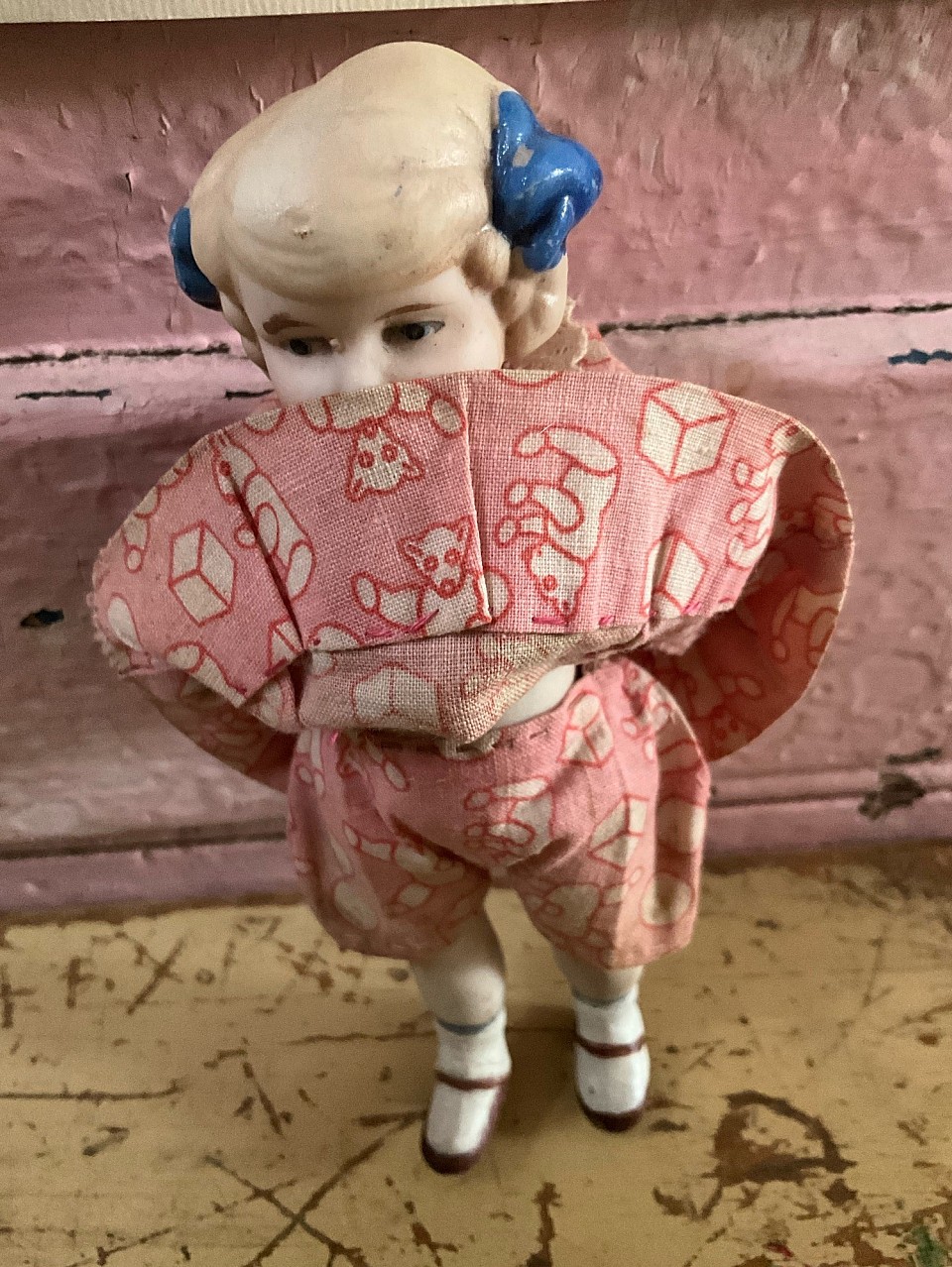 5  1/2” Antique all bisque girl with blue bows in hair. Made in Japan and wearing original pink dress & matching bloomers with teddy bear print. ~ sold